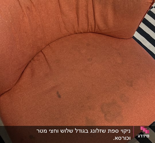 כורסה כתומה עם כתמים כהים על הבד